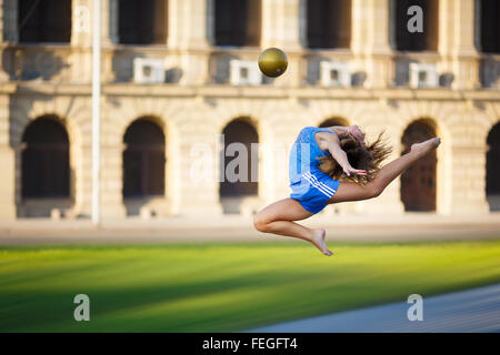 Jeune fille se divise en fait sauter avec ball Banque D'Images