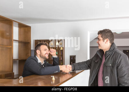 La réceptionniste et un client se serrer la main à la réception de l'auberge 24. Banque D'Images