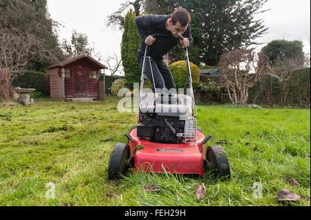 Première coupe de pelouse de l'année mal après l'hiver doux et l'herbe haute de la croissance sur une tondre le gazon avec une coupe d'essence Banque D'Images