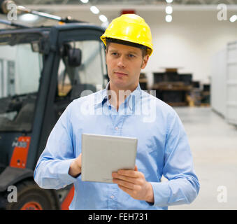 Offres in hard hat with tablet pc à l'entrepôt. Banque D'Images