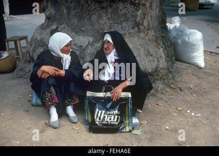 Deux générations de femme turque. Une femme turque traditionnelle habillé en costume traditionnel parle avec une jeune fille turque ou d'une jeune femme sous un platane Bursa Turquie Banque D'Images