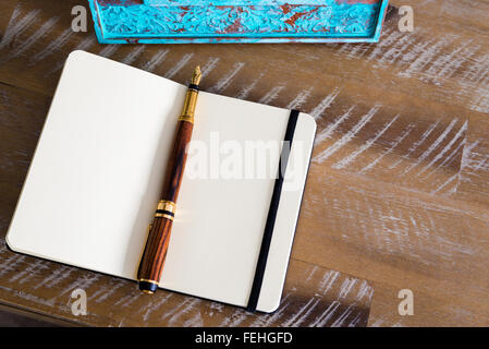 Stylo classique et ouvert sur l'ordinateur portable, table en bois avec cadre photo turquoise en arrière-plan, copie espace disponible Banque D'Images