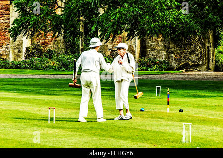 Deux dames âgées de jouer au croquet sur la pelouse devant le palais des évêques dans la région de Wells, Somerset Banque D'Images