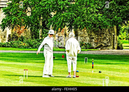 Deux dames âgées de jouer au croquet sur la pelouse devant le palais des évêques dans la région de Wells, Somerset Banque D'Images