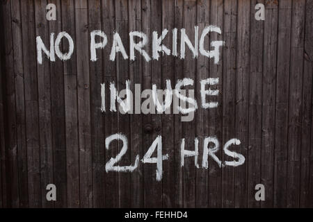 ''Pas de stationnement en usage 24 Hrs' peint en blanc sur la porte de garage en bois brun foncé. Banque D'Images