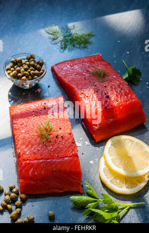 Deux morceaux de saumon sauvage darnes avec du citron, des câpres et des herbes, prêt à cuire Banque D'Images