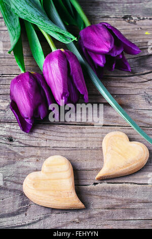 Deux coeur en bois symboliques sur fond de fleurs fraîches Banque D'Images