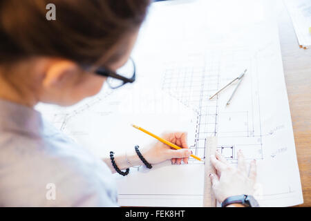 Vue supérieure, portrait d'une jeune femme ingénieur travaillant sur blueprint in office