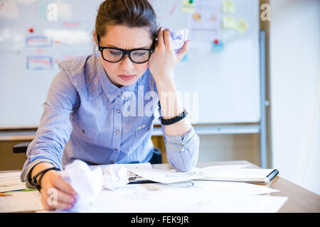 Déprimé malheureux jeune femme designer de mode et séance de travail sur le croquis dessin Banque D'Images