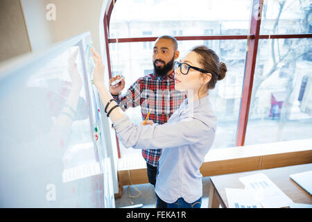 L'homme et la femme concentrée students standing et de l'écriture sur tableau blanc de classe Banque D'Images