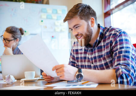 Happy young woman reading paper in office Banque D'Images