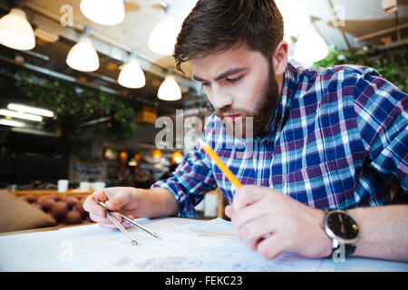 Jeune homme ingénieur travaillant sur blueprint in office Banque D'Images