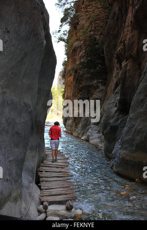 Crète, décor dans la Samarie gulch, la femme s'exécute sur une petite passerelle en bois à côté de la Brook par le ravin, la porte de fer Banque D'Images