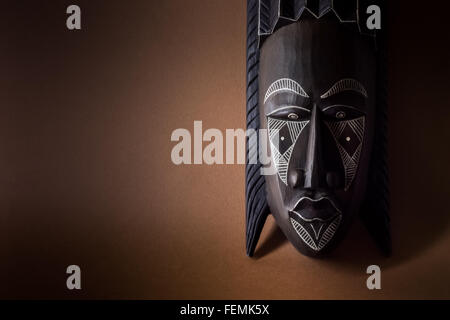 Masque en bois noir sur fond brun Banque D'Images