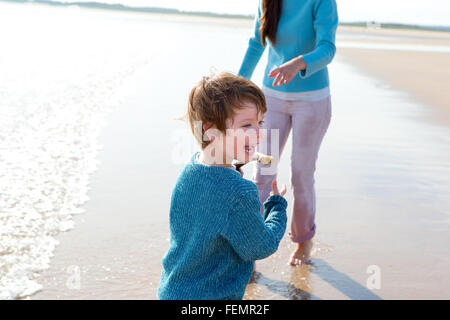 Petit Garçon jouant sur la plage avec sa mère. Banque D'Images