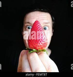 Portrait Of Man Holding Strawberry sur fond noir