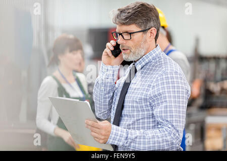 Businessman with clipboard in factory Banque D'Images