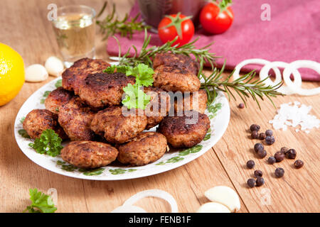 Des boulettes dans un plat servi avec divers ingrédients sur une table en bois Banque D'Images