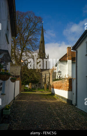 Église Thaxted, Essex, Angleterre, Royaume-Uni. Feb 2016 jusqu'à Stoney Lane, l'iconique classique vue sur l'église sans voitures. L'église paroissiale de St John, construit entre 1340 et 1510, est renommée pour son battant renforcé spire, qui est de 181 pieds de haut et est la seule pierre médiévale spire dans le comté. Windows perpendiculaires et un vitrail représentant Adam et Eve. L'église, qui se dresse sur une colline et domine la ville, est souvent appelée "la cathédrale d'Essex'.De 1910 à 1942, le vicaire a été Conrad Noel, connu sous le nom de "Vicaire Rouge" en raison de son bien connu Christian Socialis Banque D'Images