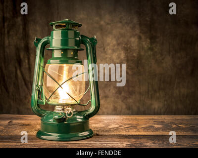 Vintage lampe à pétrole allumée sur la table en bois sur fond sombre Banque D'Images