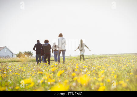 Multi-generation family walking in sunny prairie avec des fleurs sauvages Banque D'Images