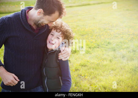 Père hugging son in field Banque D'Images