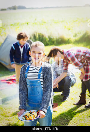 Portrait of smiling girl avec des brochettes de légumes ensoleillés au camping Banque D'Images