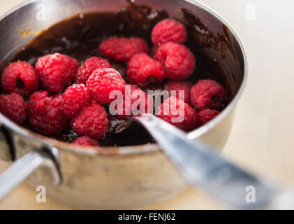 Sauce au chocolat avec des framboises dans une petite casserole Banque D'Images