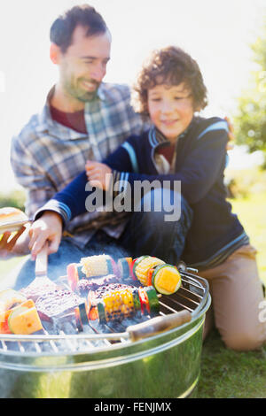 Père et fils du barbecue et brochettes de légumes Banque D'Images