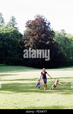 Mid adult woman et deux filles se tenant la main et running in park Banque D'Images