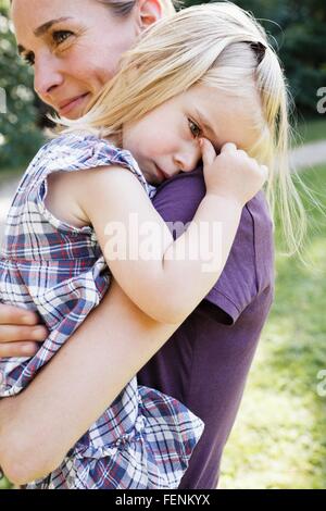 Mid adult woman carrying contrarié fille dans park Banque D'Images