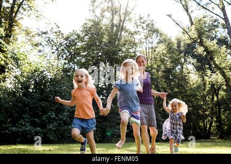 Mid adult woman et trois jeunes filles running in park Banque D'Images