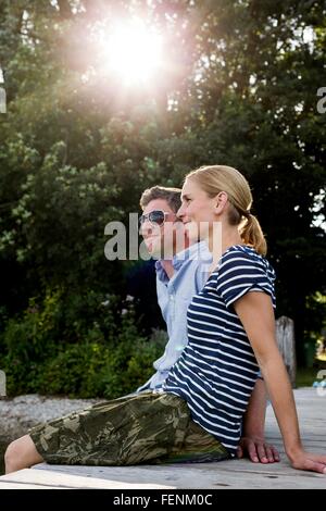 Couple sitting on wooden pier at lakeside Banque D'Images