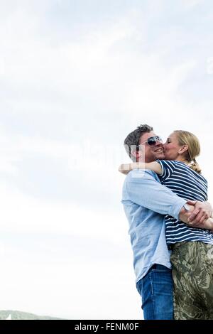 Low angle view of romantic couple hugging and kissing against sky Banque D'Images