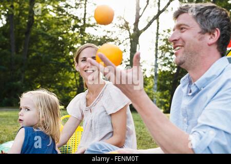 Man juggling oranges à pique-nique en famille dans la région de park Banque D'Images