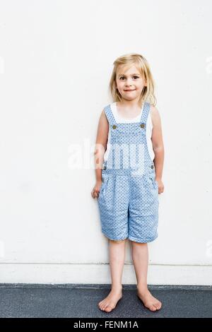 Portrait of Girl wearing salopette en face de mur blanc Banque D'Images