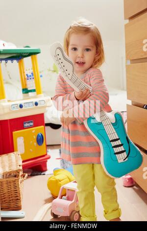 Portrait of female toddler dans jeux holding toy guitar Banque D'Images