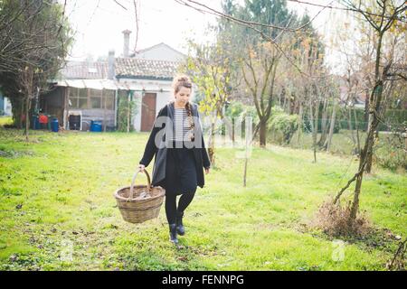 Vue avant pleine longueur de jeune femme en transportant le jardin panier osier Banque D'Images