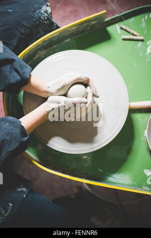 Vue de dessus de jeune femme mains sur l'argile en forme de roue de la poterie Banque D'Images