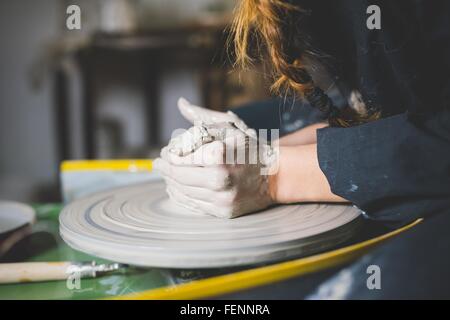 Vue latérale du jeune femme mains sur l'argile en forme de roue de la poterie Banque D'Images