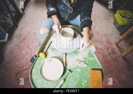 Portrait of mid adult man making clay pot sur roue de poterie Banque D'Images