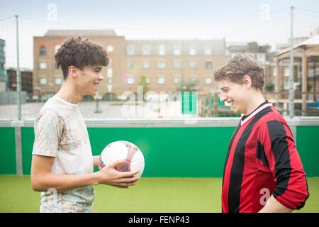 Deux jeunes hommes jouent au football sur un terrain de football urbain Banque D'Images