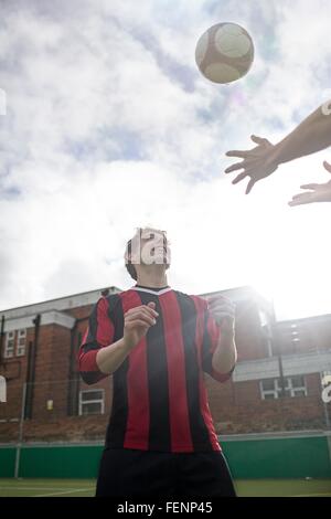 Deux jeunes hommes jouant au football sur un terrain de football urbain Banque D'Images