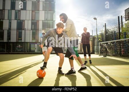 Groupe d'adultes qui jouent au football sur un terrain de football urbain Banque D'Images