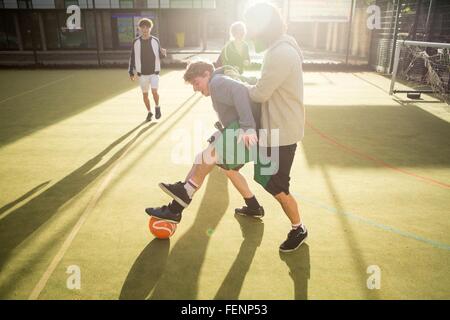 Groupe d'adultes qui jouent au football sur un terrain de football urbain Banque D'Images