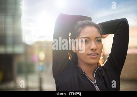 Portrait of young woman stretching, les bras derrière la tête Banque D'Images