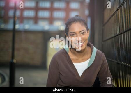 Jeune femme à côté de clôture, smiling Banque D'Images