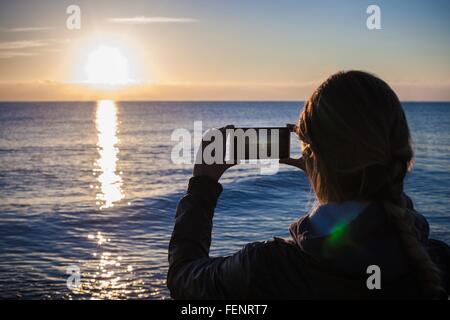 Sur la silhouette de l'épaule de la jeune femme la photographie coucher de soleil sur la mer, Villasimius, Sardaigne, Italie Banque D'Images