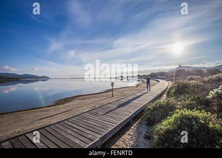 Young female runner le long Beach Boardwalk, Villasimius, Sardaigne, Italie Banque D'Images