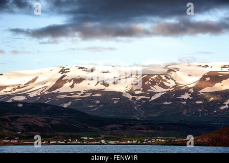 Le nord de l'Islande, Islande. 1er août 2015. Un règlement est situé sur les pentes de l'impressionnant des montagnes enneigées qui plongent dans les eaux d'¶EyjafjÃ rÃ°ur, le plus long fjord de nord de l'Islande. À côté de l'agriculture et de la pêche le tourisme est devenu un secteur en pleine croissance de l'économie et de l'Islande est devenue une destination touristique favorite. © Arnold Drapkin/ZUMA/Alamy Fil Live News Banque D'Images